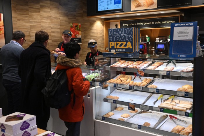 People queue at a counter inside a Greggs in central London
