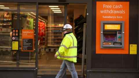 A person walks past a Sainsbury’s Bank cash machine