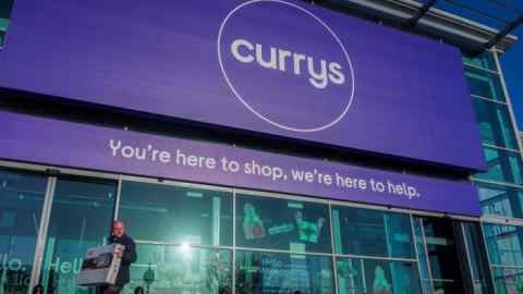 A customer carries a television outside a Currys store in London