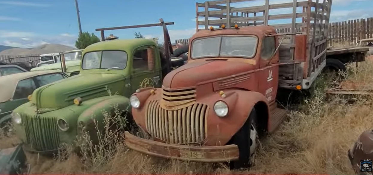 A red and a green pickup truck parked side by side